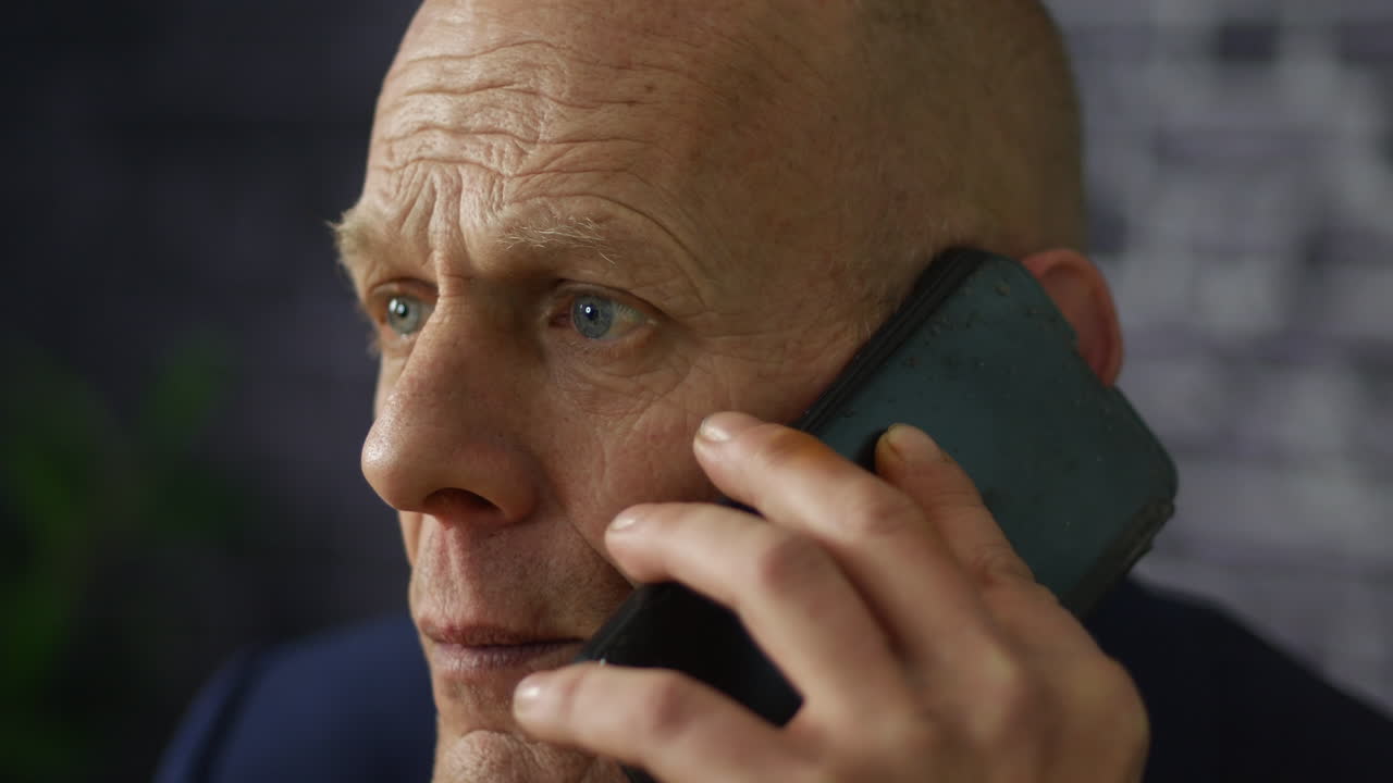 Worried mature businessman close up listening on cellphone