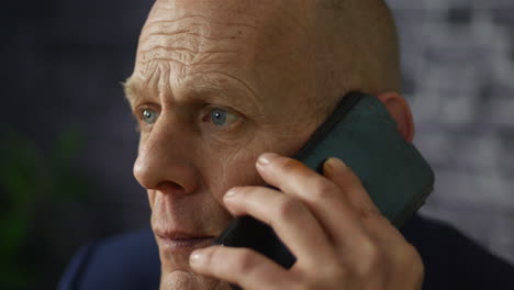 Worried-mature-businessman-close-up-listening-on-cellphone