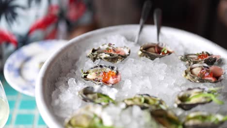 hands garnishing oysters with toppings on ice