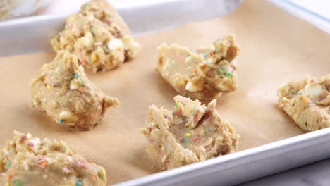 baking confetti sugar cookies and placing them on a baking sheet. making cookies and placing the batter on a sheet with a spoon to bake.. in the kitchen making a dessert