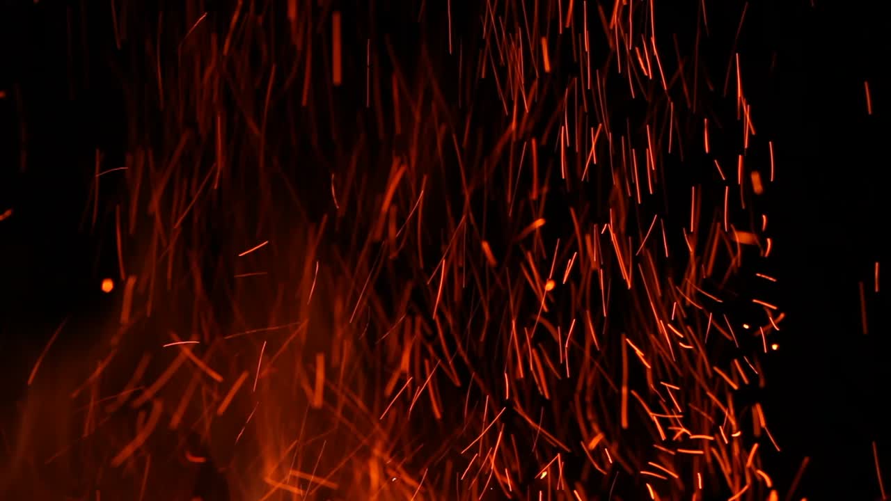 Fiery Red Sparks Flying Upwards Against a Dark Background