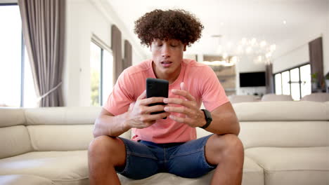 A-young-biracial-upset-and-stressed-man-is-seated-on-a-cream-sofa