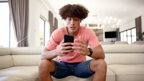 a young biracial upset and stressed man is seated on a cream sofa