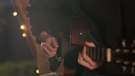 man plays the guitar and sings songs in a tent with light bulbs