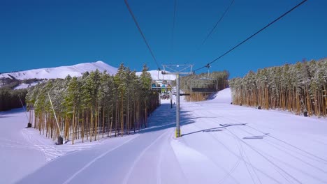 rearview of riding a ski lift or chairlift filled with skiers and snowboarders for a fun winter day at a ski resort in the rocky mountains