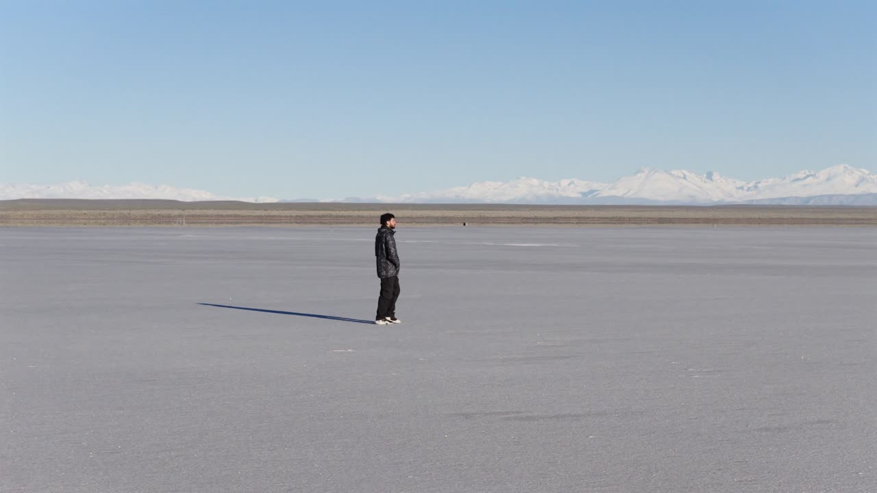 Lonely man wandering across endless white salt desert, emotional solitude concept