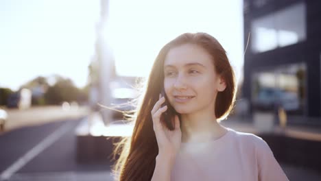 Happy-woman-talking-on-mobile-phone-outdoor,-lens-flares-on-background,-slow-motion