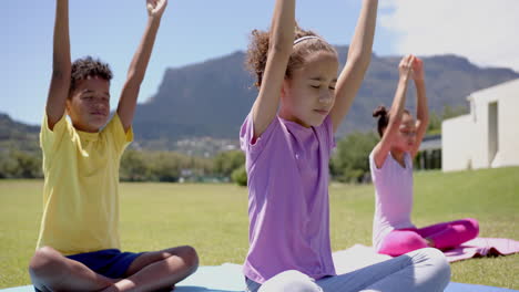 biracial children practice yoga outdoors, with mountains in the backdrop, in school