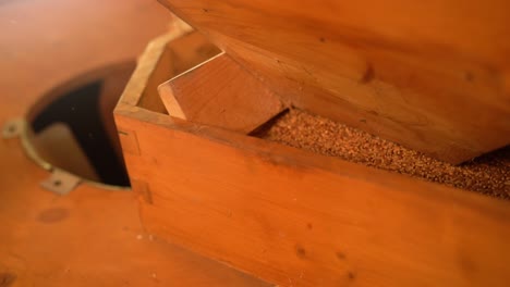 a close-up of a wooden grain storage box being filled with grains