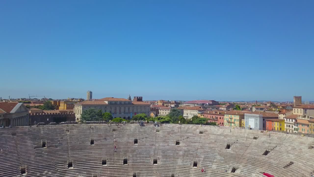 vista aérea de la arena di verona, italia. el video está hecho de un dron que se eleva desde detrás de una pared. se abre una vista de la arena y la ciudad.