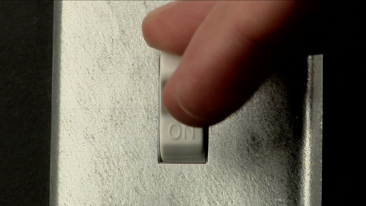 A hand turns off a light switch