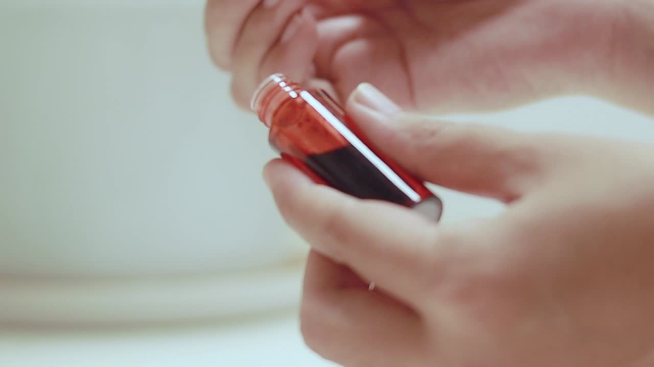 Mani che aprono e usano un tubetto di tinta labbra rossa, mostrando una routine di trucco e un prodotto di bellezza cosmetico