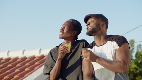 medium shot of gays sitting on rooftop and clinking glasses