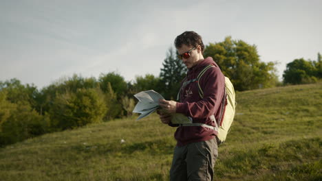 hiker looking at he paper map and then into the distance to orient himself