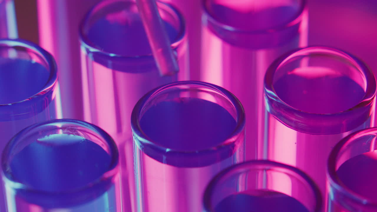 Pipette Dropping Liquid Substance into Test Tubes under Neon Light