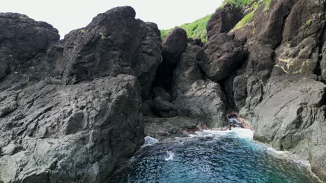 un turista aventurero salta de un acantilado rocoso a las aguas de ocean cove en filipinas - vista aérea