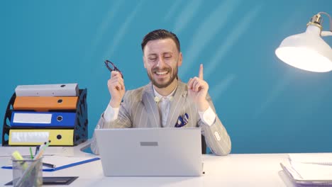 un hombre de negocios divertido y comprensivo divirtiéndose en su escritorio, sonriendo y bailando.