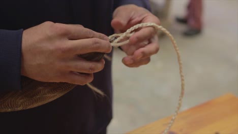 primer plano de un hombre trabajando a mano una pieza de arte tradicional maorí.