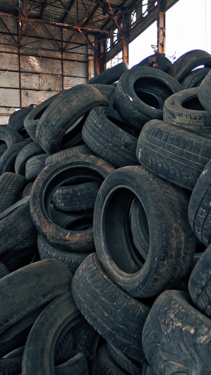 A bunch of car tires are in an abandoned factory. View of old factory inside. Close-up. Vertical video