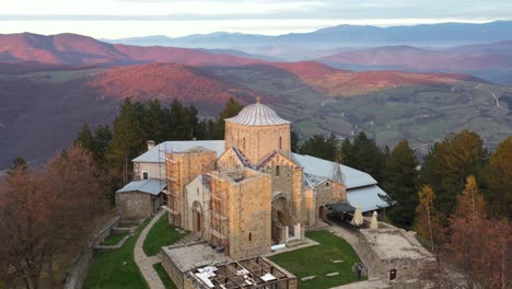 Beautiful-old-Serbian-monastery-on-mountain-peak-at-sunset,-Novi-Pazar,-aerial