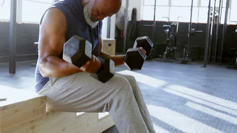 senior man exercising with dumbbell in the fitness studio 4k