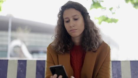 mujer joven seria usando teléfono celular al aire libre