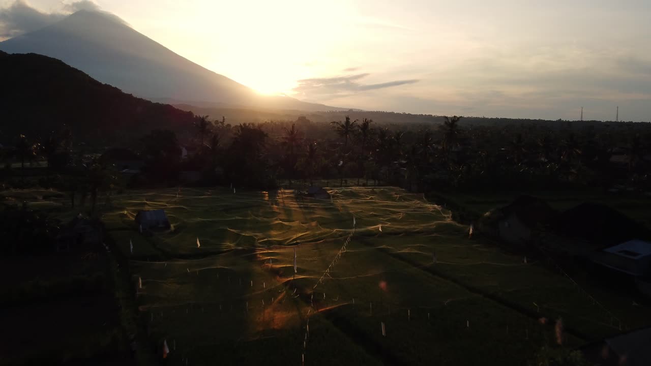 Maestoso dolly aereo in avvicinamento sul Monte Agung durante un'alba colorata su Amed, Giava Orientale