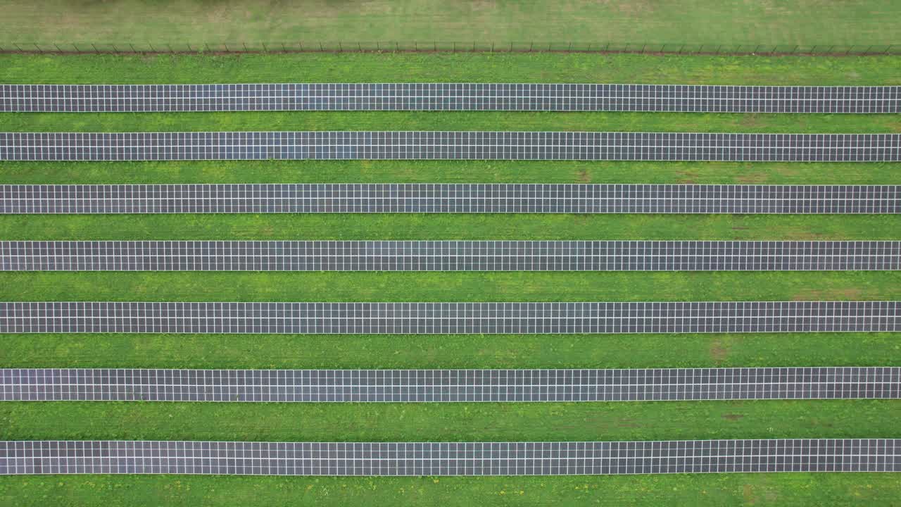 fotografía cenital de un conjunto de líneas paralelas de paneles solares construidos en un campo de hierba verde