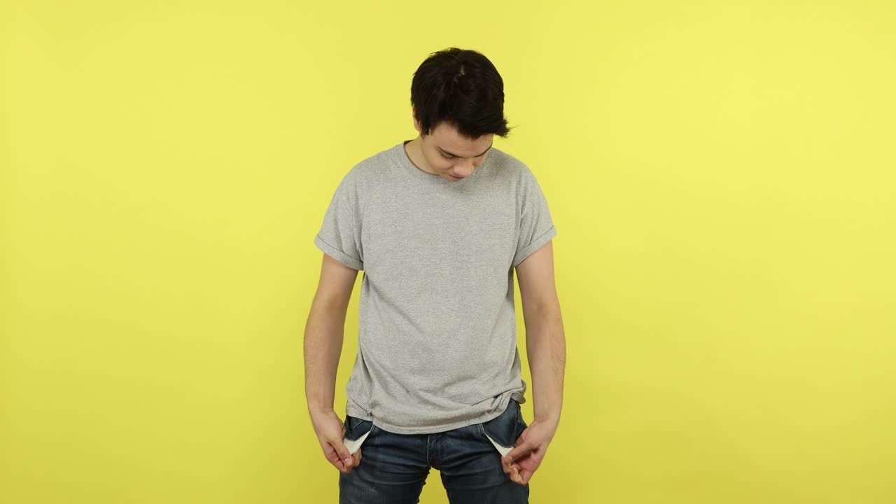 가난한 젊은이가 빈 주머니를 보여주고, 돈이 없고, 이 있고, 재정적 위기를 겪고 있습니다.