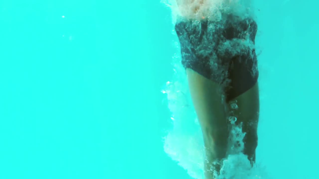 Undersøisk udsigt til atletisk mand, der dykker i swimmingpoolen