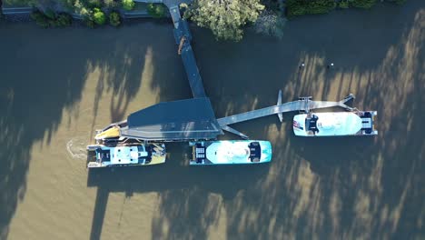 top down timelapse drone shot of 2 city cat boats leaving dock and driving away on river