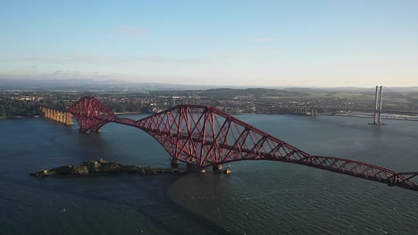 cinematic aerial angle flying towards the fourth bridge in south queensferry, scotland on a beautiful summer evening