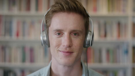 close up portrait relaxed young man student wearing headphones enjoying listening to music smiling happy in library bookstore background slow motion