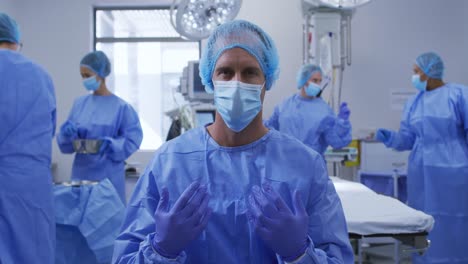 male caucasian surgeon wearing face mask, surgical cap and protective clothing in operating theatre