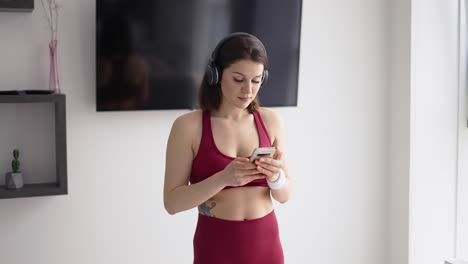 Woman-in-headphones-putting-on-music-on-mobile-for-workout
