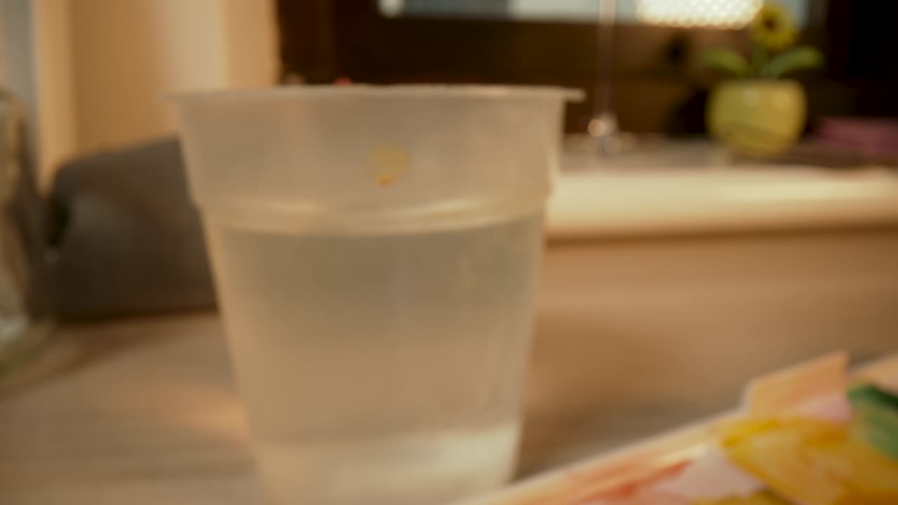 una paleta de pintura de acuarela y mojar un pincel en una taza de agua