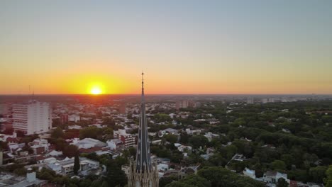 Aerial-of-a-church-spire-with-sunset-sky-and-city-background-in-San-Isidro,-Buenos-Aires