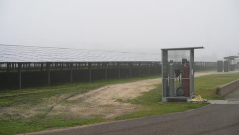 panning across modern multi angle solar panel array farm on misty countryside field