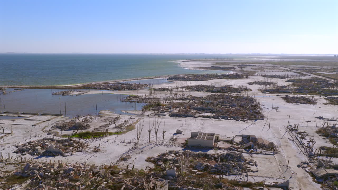 Aerial orbit around ruins of Epecuén village, revealing the vast lake and western horizon
