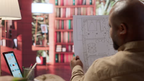 entrepreneur analyzing architectural sketches and blueprints at his home