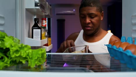 hombre comiendo sándwich del refrigerador por la noche