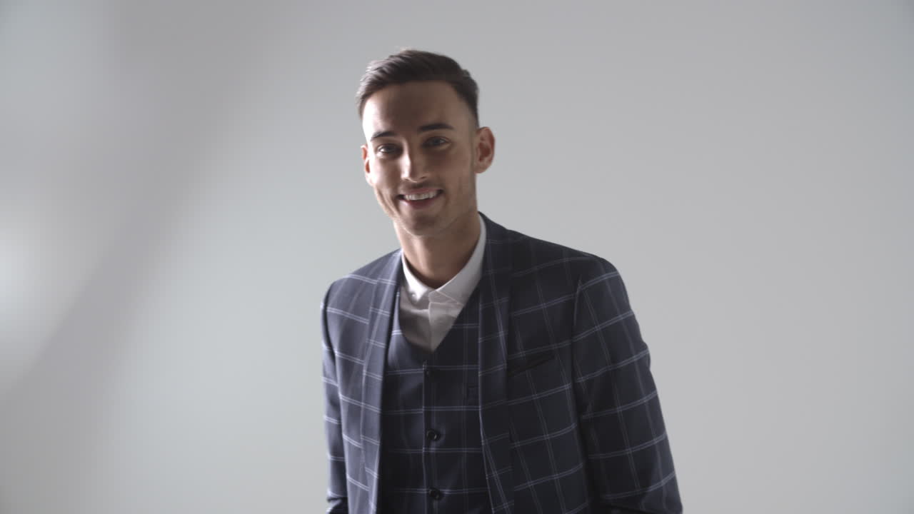 un joven de traje camina hacia la cámara, se enfoca, sonríe, gira