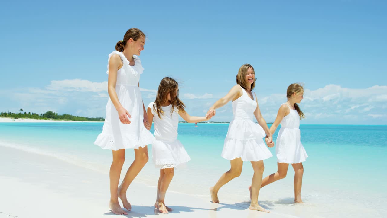 madre y hijas caucásicas caminando por la playa del caribe