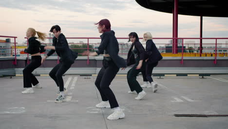 Focused-girl-group-dancing-in-black-clothing-outdoors