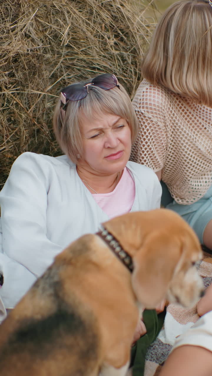 가족은 야외에서 조용한 순간을 즐기고, 야외에서 풀 근처에서 휴식을 취하고, 사려 깊은 여자가 멀리 쳐다보고, 다른 한 명은 뒤로 기대고, 아이는 읽기 위해 누워 있습니다.