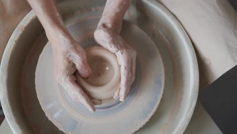 female potter makes a pot on the pottery wheel.