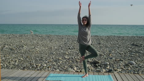 mujer practicando yoga en una playa
