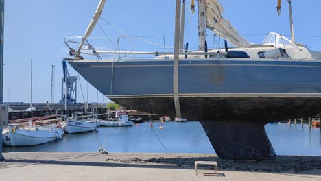 4k-60fps-Segelboot-Auf-Einem-Lift-In-Einem-Hafen-In-Schweden-Während-Der-Wartung-Des-Kiels-–-LKW-Aufnahme