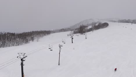 timelapse stationary shot of an open air chair lift carrying passengers to the top of a ski slope.