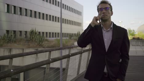 good looking young man walking outside, talking on phone